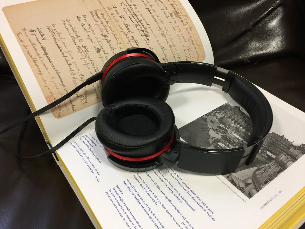 Cómo crear audiolibros con IA - Un par de auriculares colocados encima de un libro abierto, lo que demuestra cómo crear audiolibros con IA.