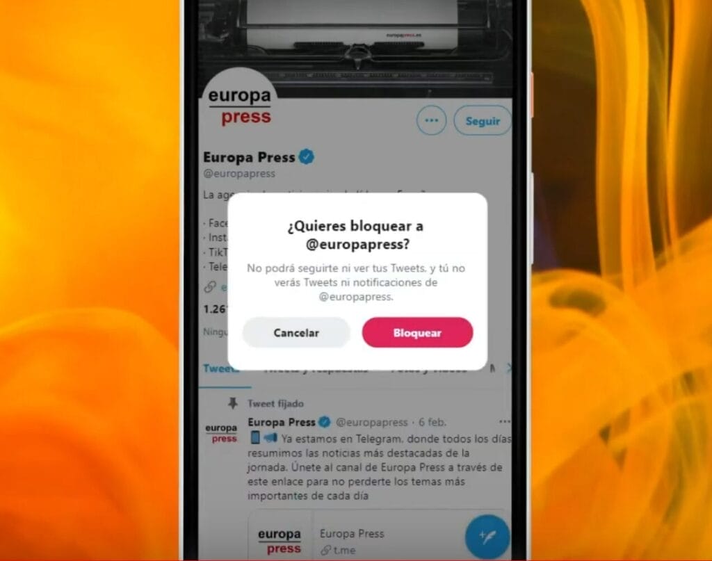 como bloquear a alguien en twitter -- La pantalla de un teléfono muestra un hilo de Twitter con un mensaje emergente de confirmación que dice "¿Quieres bloquear a @europapress?" Las opciones son "Cancelar" y "Bloquear". Esto ilustra el proceso de "cómo bloquear un usuario en Twitter".